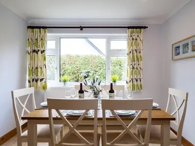 a dining room with a table and chairs and a window at Longhouse Bungalow in Polzeath