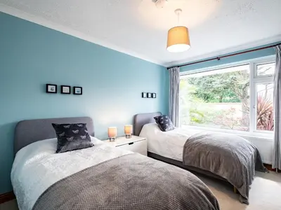 two beds in a room with blue walls and a window at Longhouse Bungalow in Polzeath