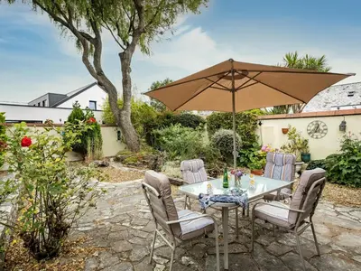 a table and chairs with an umbrella in a yard at Longhouse Bungalow in Polzeath