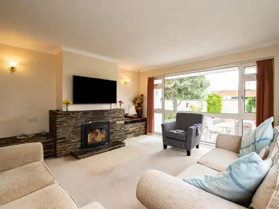 a living room with a fireplace and a flat screen tv at Longhouse Bungalow in Polzeath