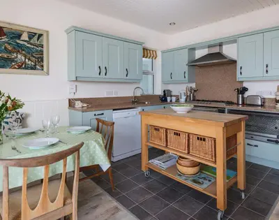 a kitchen with blue cabinets and a table and a table and chairs at Carn Du 1 in Padstow