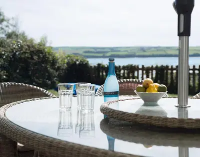 a table with glasses and a bottle and a bowl of fruit at Carn Du 1 in Padstow