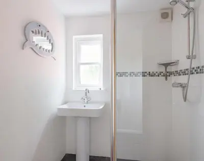 a white bathroom with a sink and a shower at Conifers in Saint Minver