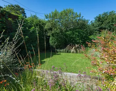 a garden with a field of grass and flowers at Conifers in Saint Minver