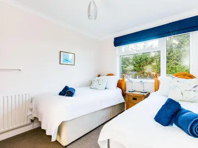two beds in a room with a window at Little Sailing in Padstow