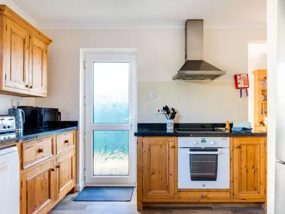 a kitchen with wooden cabinets and a stove top oven at Little Sailing in Padstow