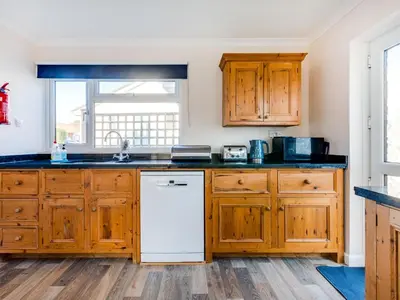 a kitchen with wooden cabinets and a white dishwasher at Little Sailing in Padstow