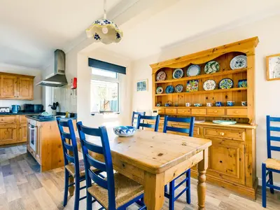 a kitchen with a wooden table and chairs at Little Sailing in Padstow