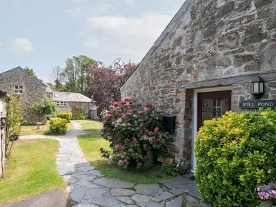 a stone building with a door with flowers on it at Mill Pond in Saint Minver