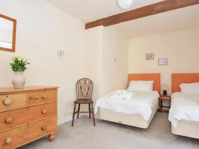 a bedroom with two beds and a dresser and a chair at Mill Pond in Saint Minver