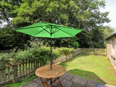 a green umbrella sitting on a table in a yard at Mill Pond in Saint Minver