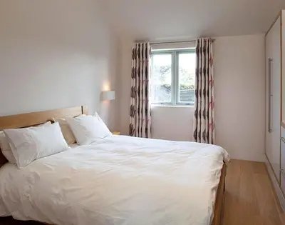 a bedroom with a large white bed and a window at Downalong in Polzeath