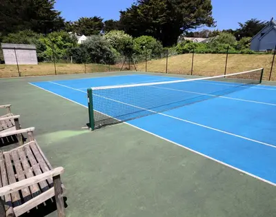 a tennis net on a tennis court with a bench at Downalong in Polzeath