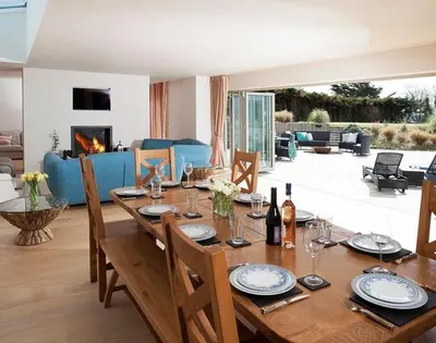 a wooden dining table with chairs and a living room at Downalong in Polzeath