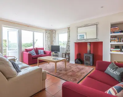 a living room with red furniture and a fireplace at Kirra in Polzeath