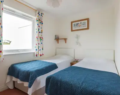 two beds in a room with a window at Kirra in Polzeath