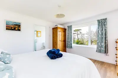 a bedroom with a white bed and a window at Rock Hill in Padstow