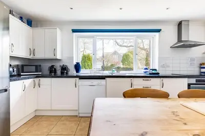 a kitchen with white cabinets and a large window at Rock Hill in Padstow