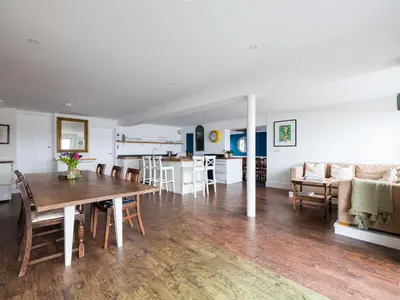 a dining room and living room with a table and a couch at Treverden in Polzeath