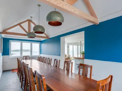 a dining room with a large wooden table and chairs at Treverden in Polzeath