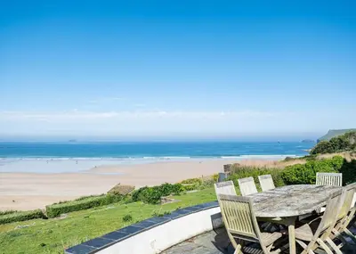 a table with chairs and a view of a beach at Treverden in Polzeath