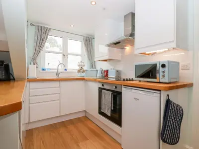 a kitchen with white cabinets and a microwave at Smugglers Loft in Looe