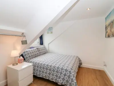 a small bedroom with a bed and a table at Smugglers Loft in Looe