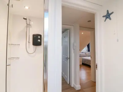 a bathroom with a walk in shower next to a bedroom at Smugglers Loft in Looe