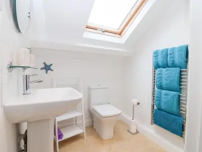 a bathroom with a sink and a toilet and a window at Smugglers Loft in Looe