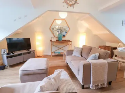 a living room with a couch and a tv at Smugglers Loft in Looe