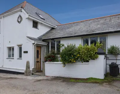 a white house with flowers in front of it at Fairholme in Port Isaac