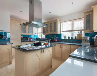 a large kitchen with wooden cabinets and a large island at Fairholme in Port Isaac