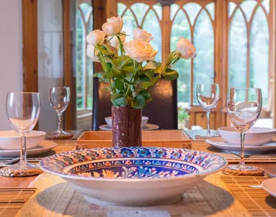 a table with a vase of flowers on a table with glasses at Fairholme in Port Isaac