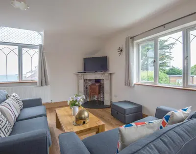 a living room with two blue couches and a fireplace at Fairholme in Port Isaac