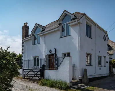 a white house with blue windows and a gate at Fairholme in Port Isaac