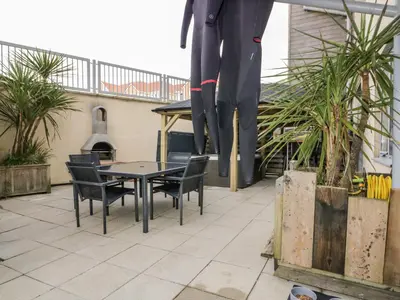 a table and chairs on a patio with a statue at Fistral Apres Surf in Newquay