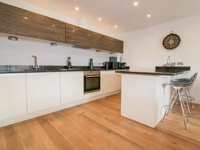 a kitchen with white cabinets and a clock on the wall at Fistral Apres Surf in Newquay