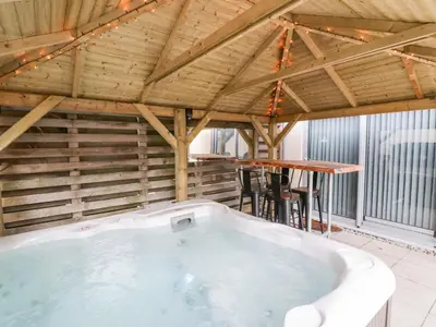 a hot tub in a room with a wooden ceiling at Fistral Apres Surf in Newquay