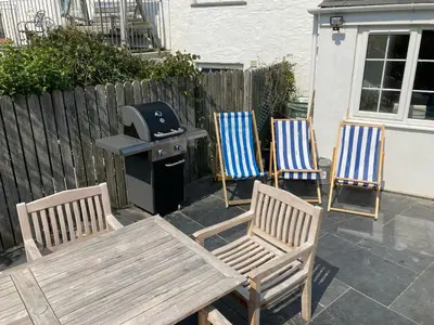 three chairs and a table and a grill on a patio at Beehive Cottage in Port Isaac