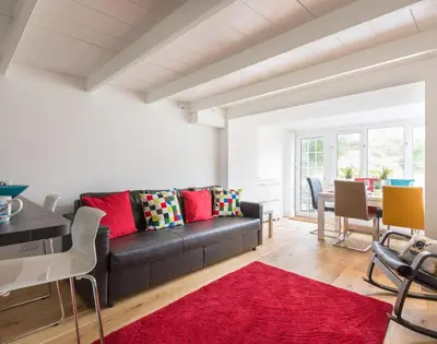 a living room with a black couch and a red rug at Beehive Cottage in Port Isaac