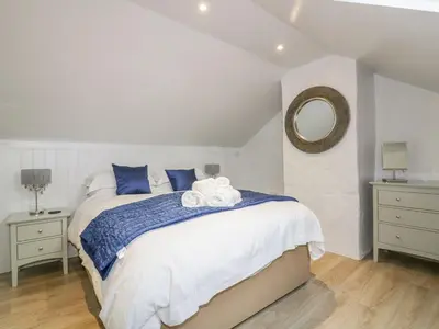 a bedroom with a bed with blue pillows and a mirror at Apple Barn in Newquay
