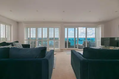 a living room with two blue couches and a television at Sandbanks in Penzance