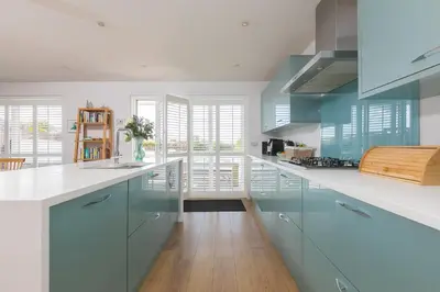 a kitchen with blue cabinets and white counter tops at Sandbanks in Penzance