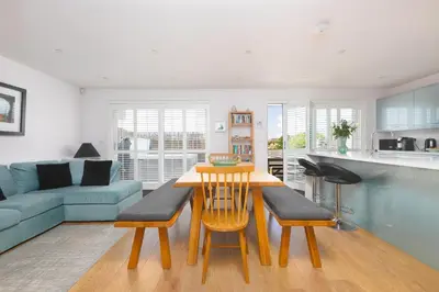 a kitchen and living room with a table and chairs at Sandbanks in Penzance