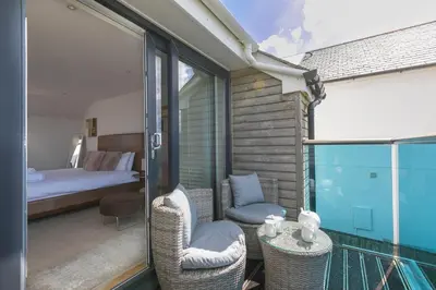 a room with a balcony with a bed and chairs at Sandbanks in Penzance