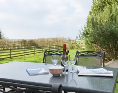 a table with a bottle of wine and two glasses at Lundy Cottage in Saint Minver