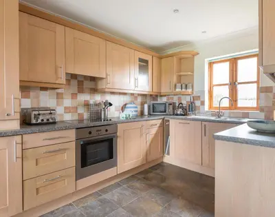 a large kitchen with wooden cabinets and appliances at Lundy Cottage in Saint Minver