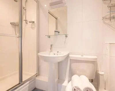 a white bathroom with a sink and a toilet and a shower at Lundy Cottage in Saint Minver