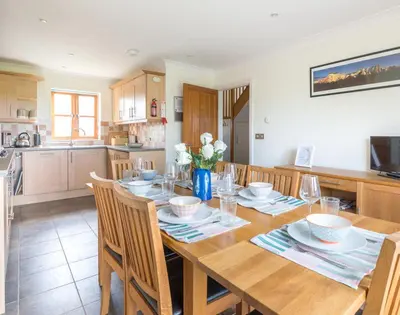 a kitchen with a wooden table with chairs and a dining room at Lundy Cottage in Saint Minver