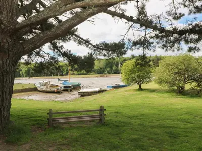 a park bench in a field with boats in the water at Armando in Truro
